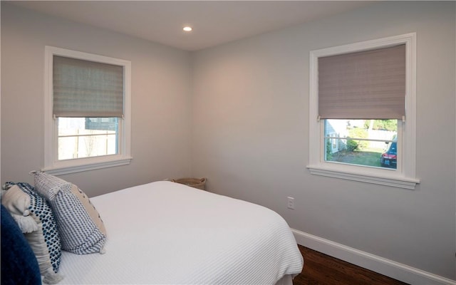 bedroom with dark hardwood / wood-style flooring and multiple windows