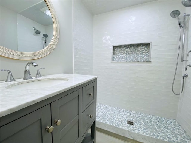 bathroom with a tile shower and vanity