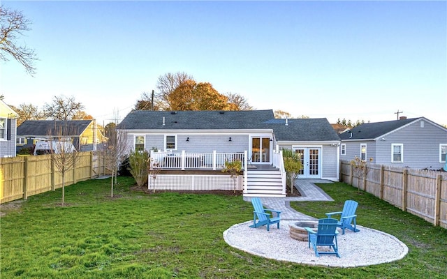 back of property with french doors, a fire pit, a lawn, and a wooden deck