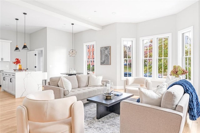 living room featuring beamed ceiling and light hardwood / wood-style floors