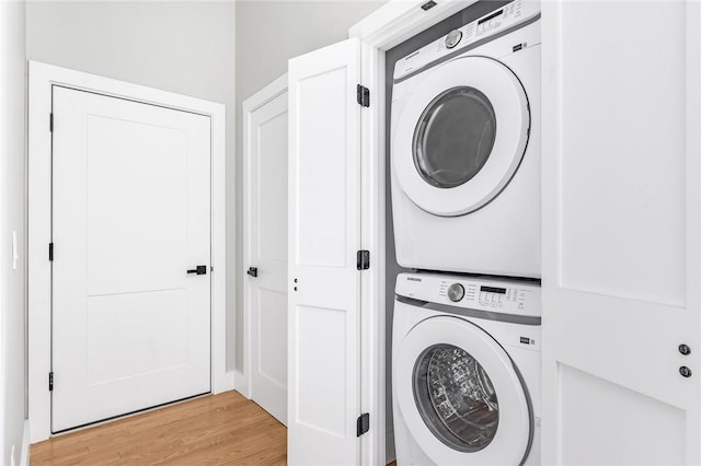 washroom with light hardwood / wood-style flooring and stacked washer / drying machine