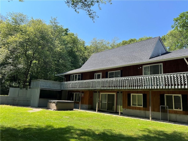 back of house featuring a hot tub and a lawn