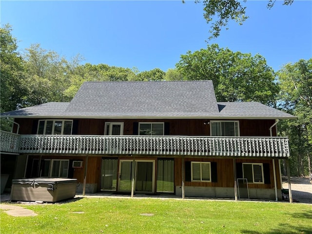 back of house with a hot tub, a patio area, and a lawn