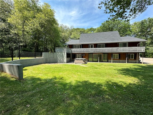 rear view of property featuring a jacuzzi and a yard