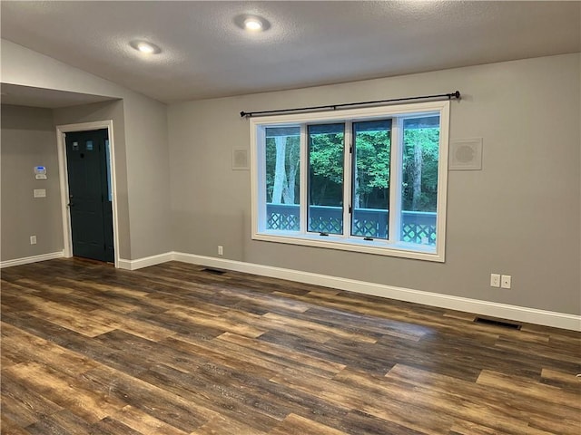 unfurnished room with a textured ceiling, dark hardwood / wood-style flooring, and lofted ceiling