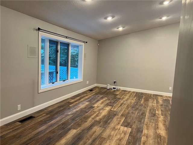 unfurnished room featuring dark hardwood / wood-style flooring and a textured ceiling