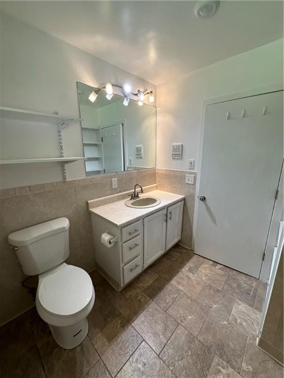 bathroom featuring vanity, toilet, and tile walls