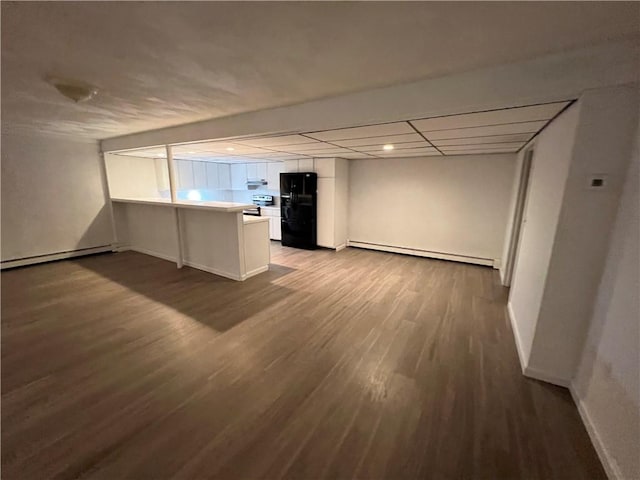 interior space featuring kitchen peninsula, black fridge, white cabinets, and a baseboard radiator