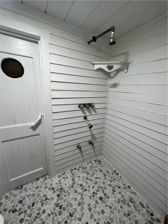 bathroom featuring walk in shower and wood walls