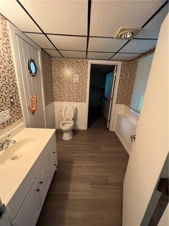 bathroom featuring vanity, toilet, a drop ceiling, and wood-type flooring