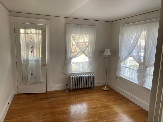 entrance foyer with radiator heating unit and hardwood / wood-style flooring