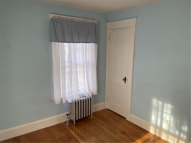 spare room with hardwood / wood-style flooring and radiator heating unit