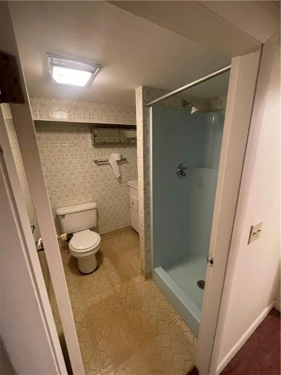 bathroom with toilet and a tile shower