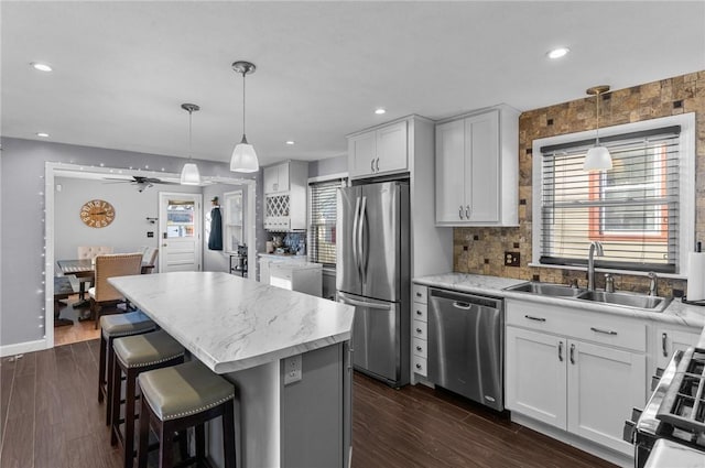 kitchen with decorative light fixtures, white cabinetry, sink, and appliances with stainless steel finishes