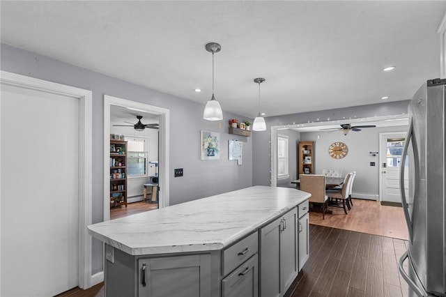 kitchen featuring gray cabinetry, dark hardwood / wood-style floors, stainless steel fridge, decorative light fixtures, and a kitchen island