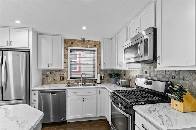 kitchen with hanging light fixtures, white cabinetry, sink, and appliances with stainless steel finishes