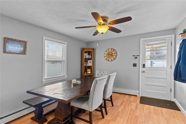 dining space featuring light hardwood / wood-style floors, ceiling fan, and a baseboard heating unit