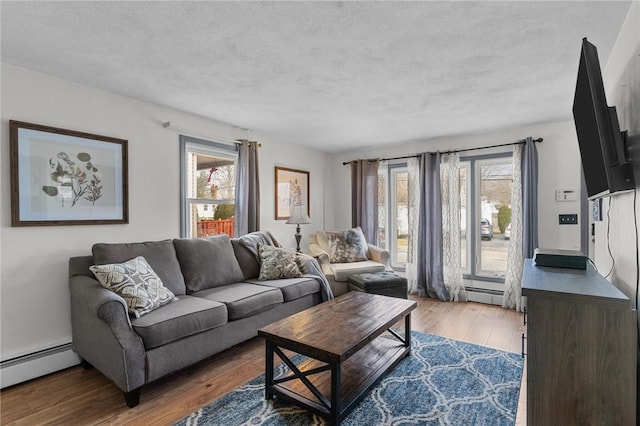 living room featuring dark wood-type flooring, a textured ceiling, and a baseboard heating unit