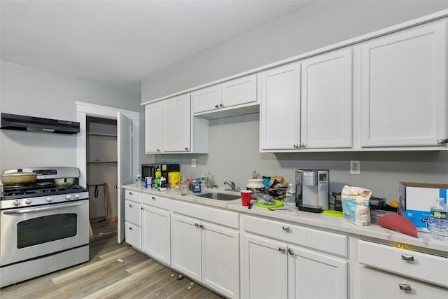 kitchen featuring stainless steel range with gas cooktop, sink, light hardwood / wood-style floors, white cabinetry, and range hood