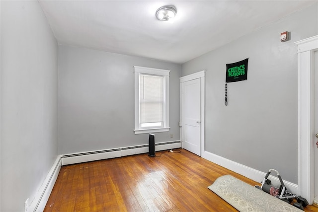 empty room with wood-type flooring and baseboard heating