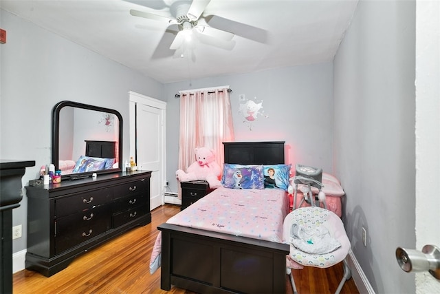 bedroom with ceiling fan, light hardwood / wood-style floors, and baseboard heating