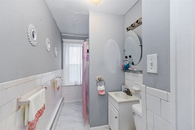 bathroom with tile walls, vanity, a baseboard heating unit, and toilet