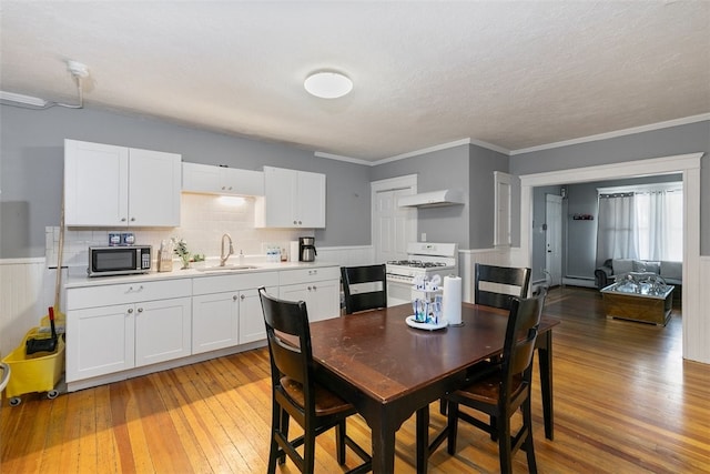 dining area with a textured ceiling, light hardwood / wood-style floors, crown molding, and sink