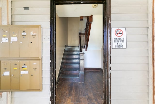 staircase with mail boxes, wood-type flooring, and wood walls