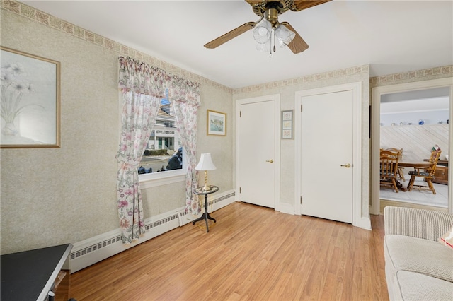 foyer entrance featuring ceiling fan, a baseboard radiator, and light hardwood / wood-style floors