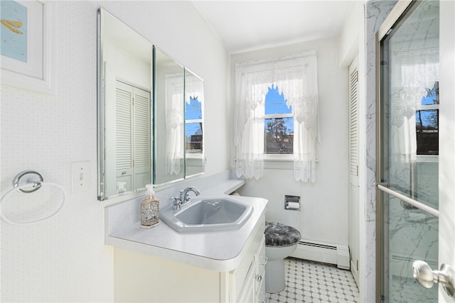 bathroom featuring vanity, toilet, a shower with door, and baseboard heating