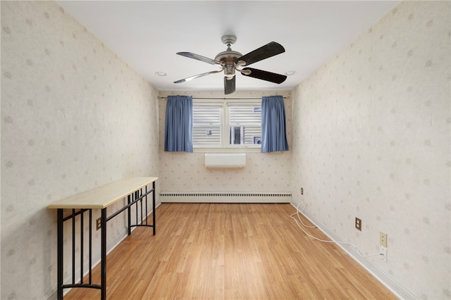 spare room with hardwood / wood-style flooring, ceiling fan, a wall mounted AC, and a baseboard heating unit