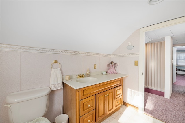 bathroom featuring toilet, vanity, vaulted ceiling, and radiator