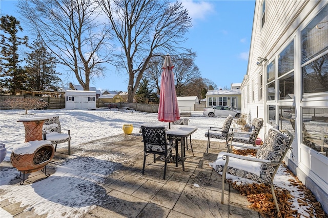 snow covered patio featuring a shed