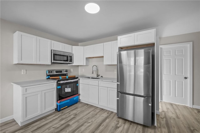 kitchen with sink, white cabinets, light hardwood / wood-style floors, and appliances with stainless steel finishes