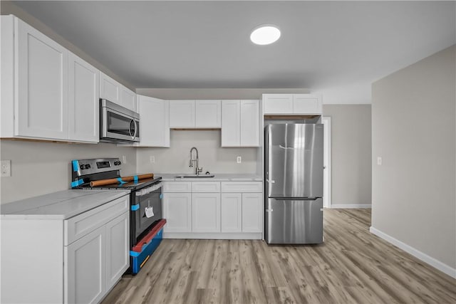 kitchen featuring white cabinetry, sink, light wood-type flooring, and appliances with stainless steel finishes