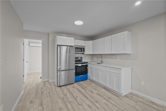 kitchen featuring white cabinets, appliances with stainless steel finishes, light hardwood / wood-style flooring, and sink