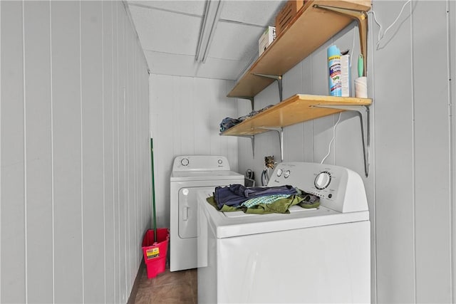 clothes washing area featuring wooden walls and washer and clothes dryer