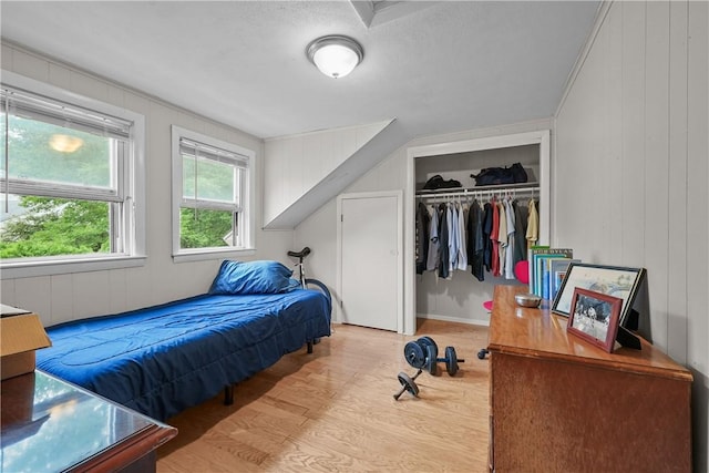 bedroom featuring light hardwood / wood-style flooring, a closet, and wood walls