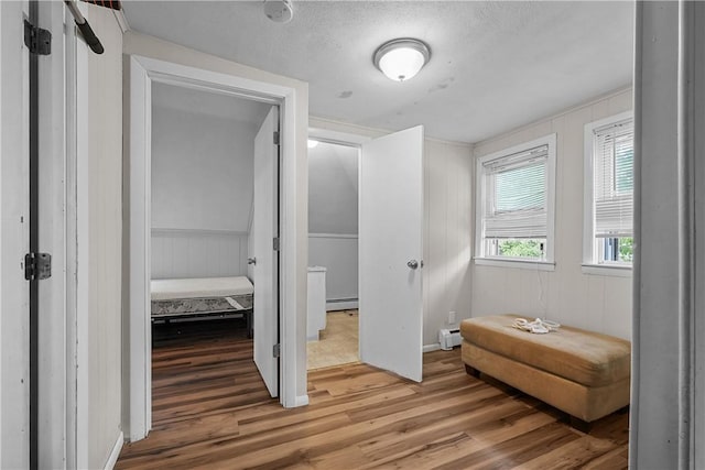 interior space with baseboard heating, a textured ceiling, and hardwood / wood-style flooring