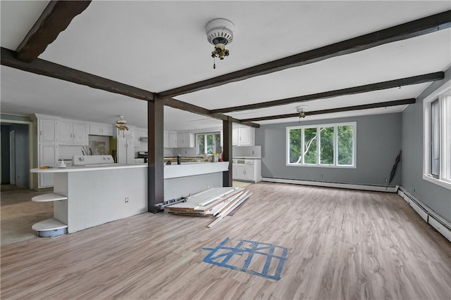 unfurnished living room with beamed ceiling, light wood-type flooring, a baseboard radiator, and a healthy amount of sunlight