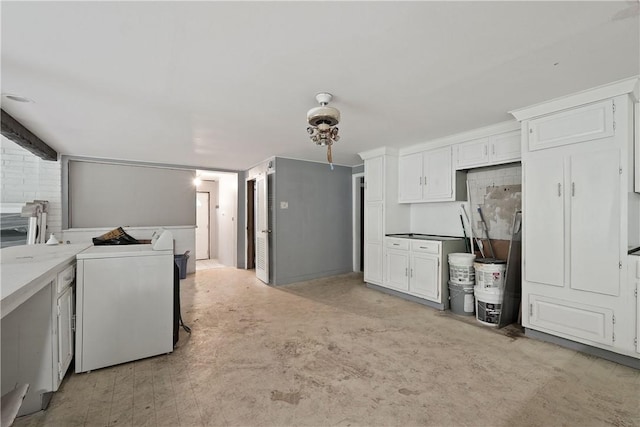 kitchen with independent washer and dryer and white cabinetry