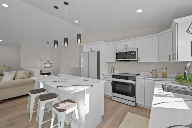 kitchen with stainless steel refrigerator, electric range, decorative light fixtures, lofted ceiling, and white cabinets