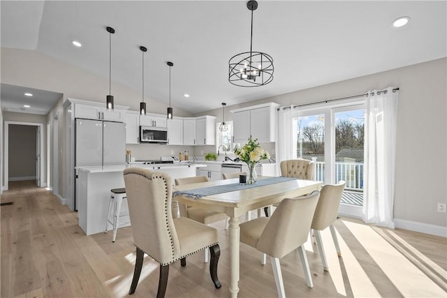 dining space featuring a notable chandelier, sink, vaulted ceiling, and light wood-type flooring