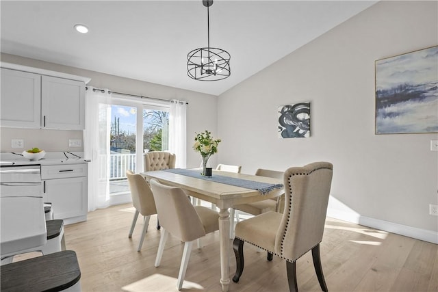 dining room with vaulted ceiling, light wood-type flooring, and an inviting chandelier