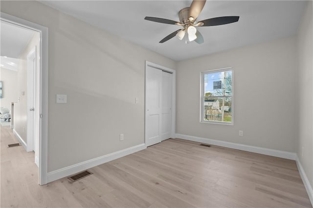 unfurnished bedroom featuring ceiling fan, a closet, and light wood-type flooring