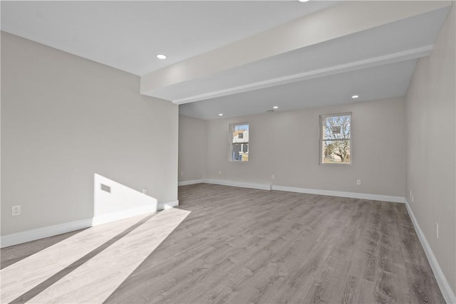 unfurnished room featuring beamed ceiling and light hardwood / wood-style flooring