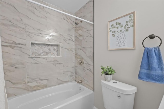 bathroom featuring tiled shower / bath combo and toilet