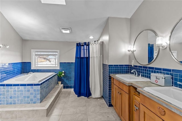 bathroom with tile patterned floors, vanity, and a relaxing tiled tub