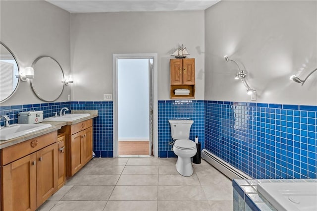 bathroom with baseboard heating, tile patterned floors, toilet, vanity, and tile walls