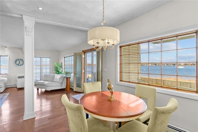 dining room with baseboard heating, ornate columns, a water view, and an inviting chandelier